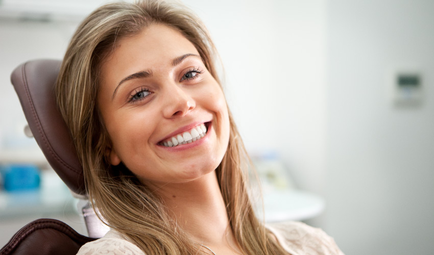 Brunette woman smiles in a dental chair after receiving periodontal therapy to improve her gum health after gum disease
