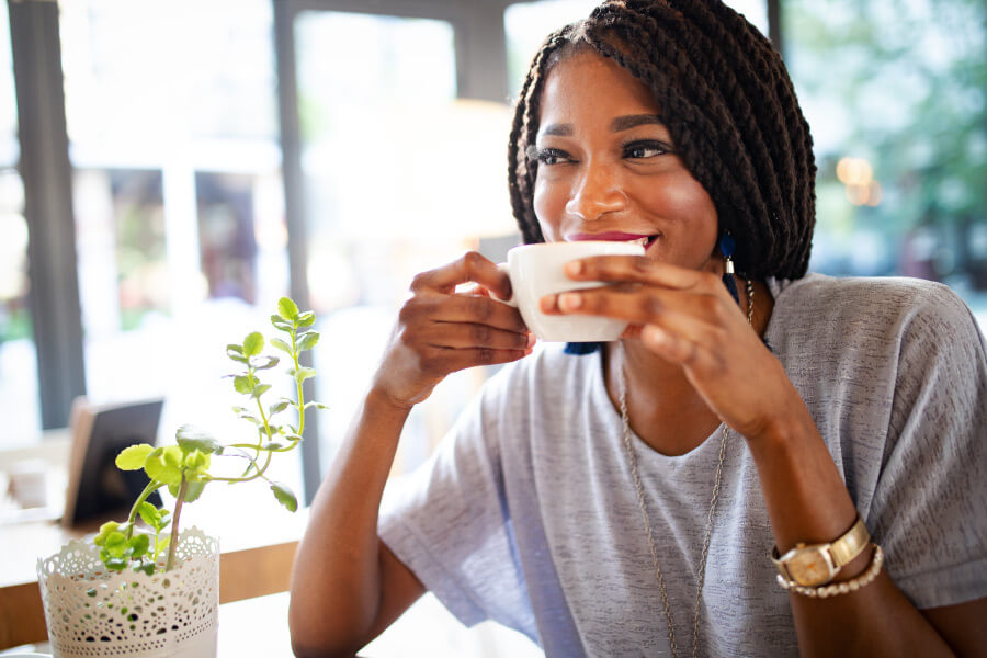 Dark-haired woman smiles while drinking a coffee alternative in a white mug in Henderson, NV